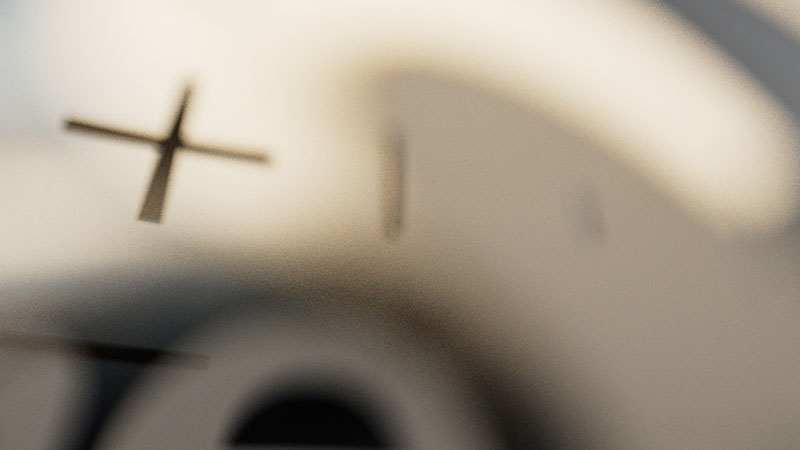 An abstract look-development frame featuring a sharp black crosshair graphic in the foreground with heavy lens blur and bokeh obscuring the background layout.