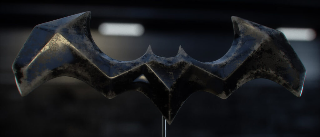 Prop Design and Metallurgical Look-Development A wide close-up studio render of the custom 3D Batarang model, highlighting the intense surface texturing with a heavily pitted, dark iron centre chassis contrasted against highly polished, sharp metallic wing edges under dramatic rim lighting.