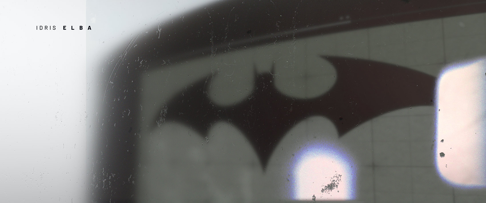 A motion graphics style frame showing a dark, redesigned bat logo visible through a hazy monitor interface with subtle screen textures, paired with a placeholder cast credit layout and light leaks.