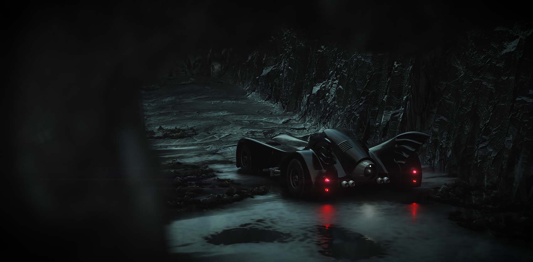 A high-angle cinematic 3D render of the Tim Burton Batmobile parked on a dark, wet mud track surrounded by rocky cliffs at night, showing the glowing red rear tail lights reflecting on the damp ground.