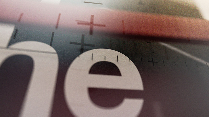 A shallow depth of field style frame focusing on bold white typography overlaid with fine crosshair grid lines and a blurred red horizontal bar element.