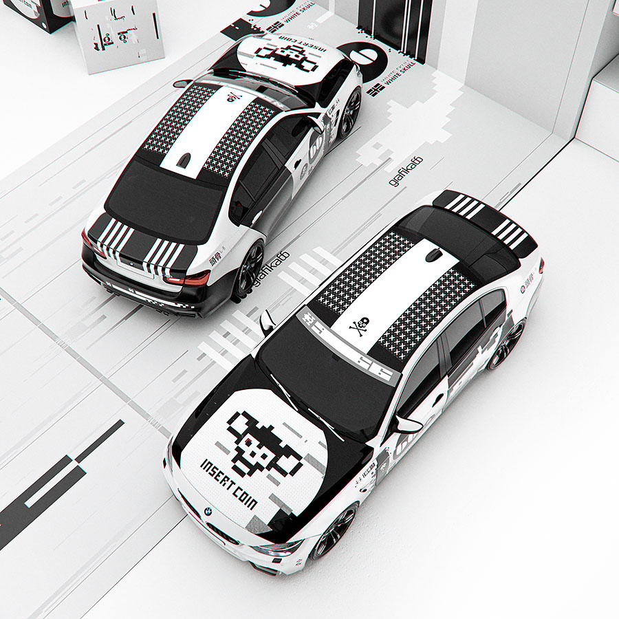 A high-angle studio shot looking down at two modern sports cars with an asymmetric monochrome livery design parked in a clean white environment.
