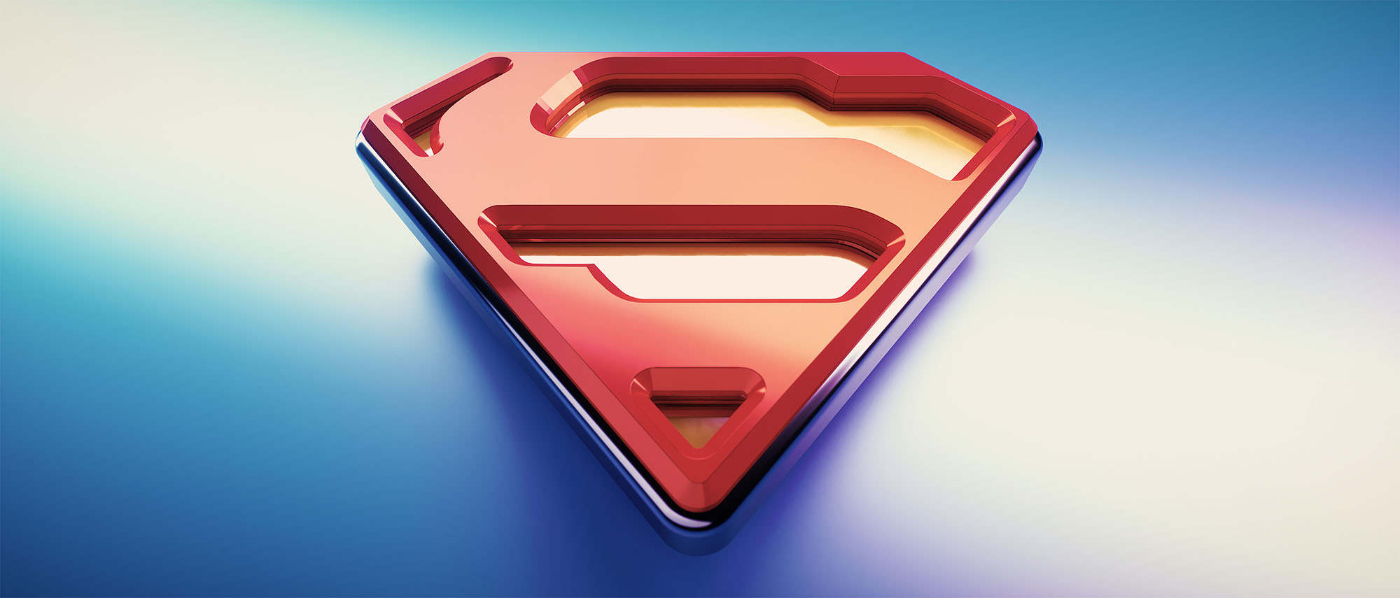 A clean, vibrant 3D look-development render of the Superman shield logo using a contemporary red and yellow colour palette with a high-gloss reflective finish, set against a smooth blue and white gradient background.