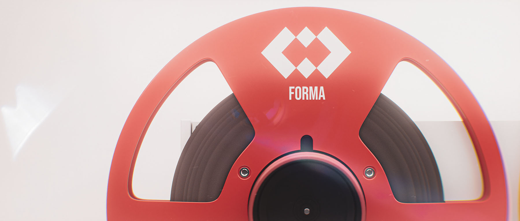 Perfectly centered widescreen view of the upper half of a red metallic audio reel showcasing the clean geometric lines of the Forma branding emblem.
